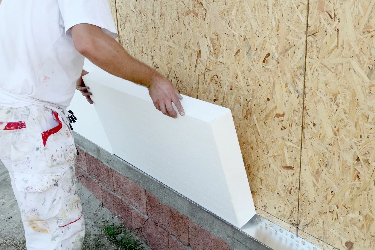 Man placing spray foam block on wall